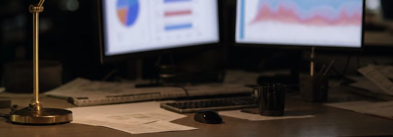 Dos monitores con gráficos desenfocados en una sala de redacción